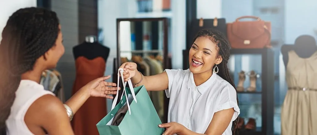 young store owner handing a parcel to a customer over the counter