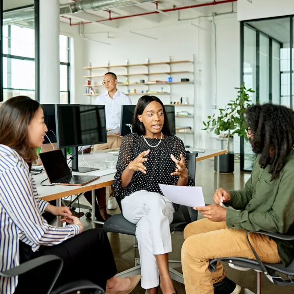 three seated female co-workers discussing data analytics